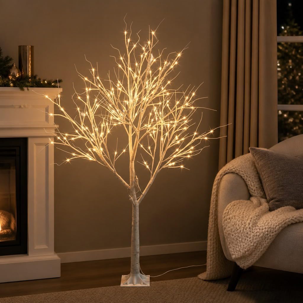 White birch-style LED tree with warm fairy lights in a living room corner by a fireplace