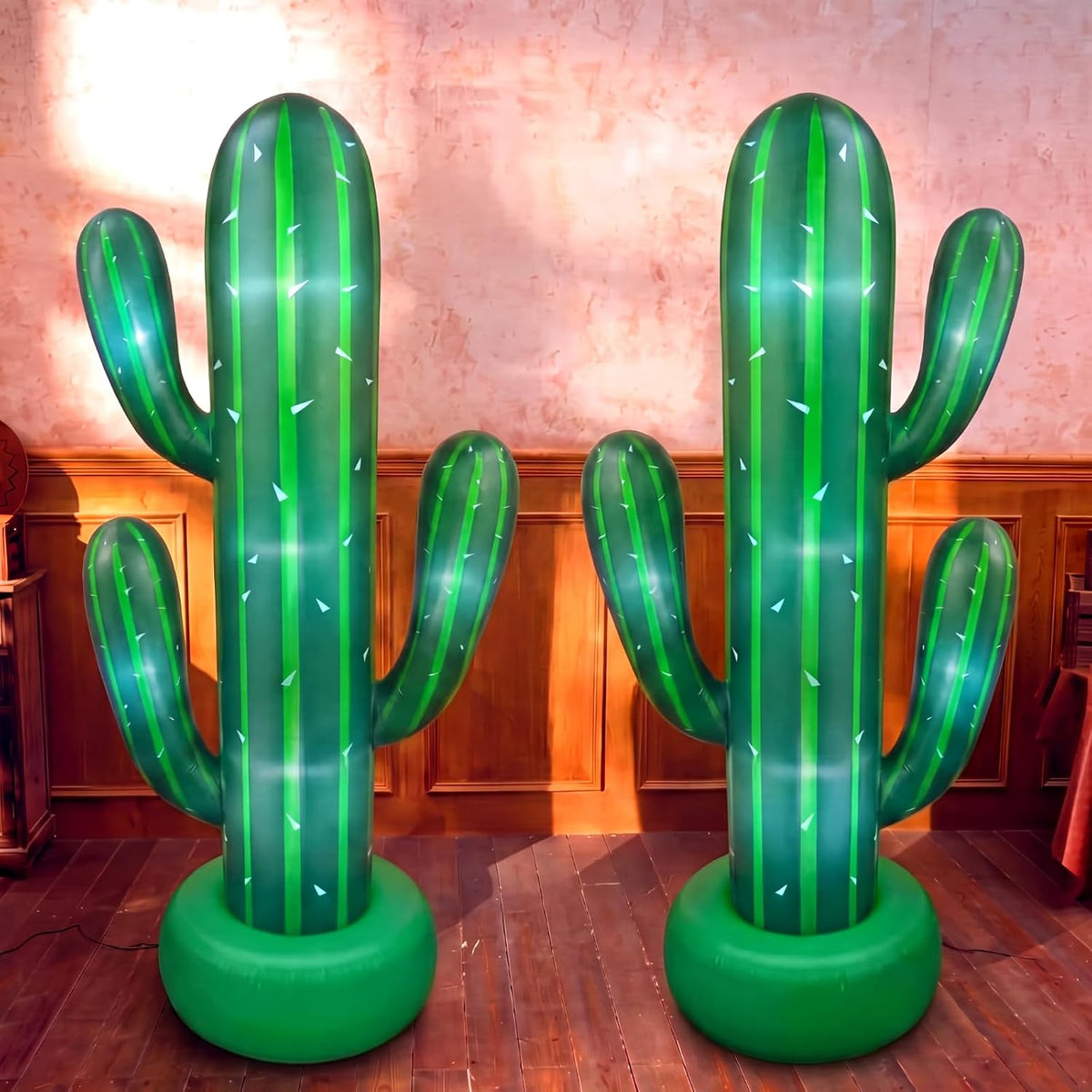 Two tall green inflatable saguaro cactus props in green pots, lit from inside