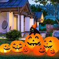 Row of glowing jack-o'-lantern inflatables with a black cat in a witch hat on top in front of a house