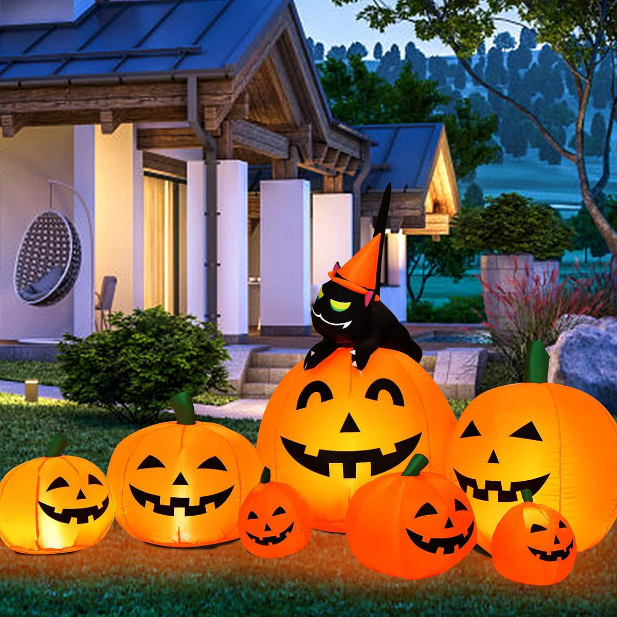 Row of glowing jack-o'-lantern inflatables with a black cat in a witch hat on top in front of a house