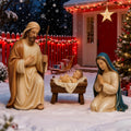 Painted nativity figures of Joseph, Mary kneeling and the baby Jesus in a manger in the snow