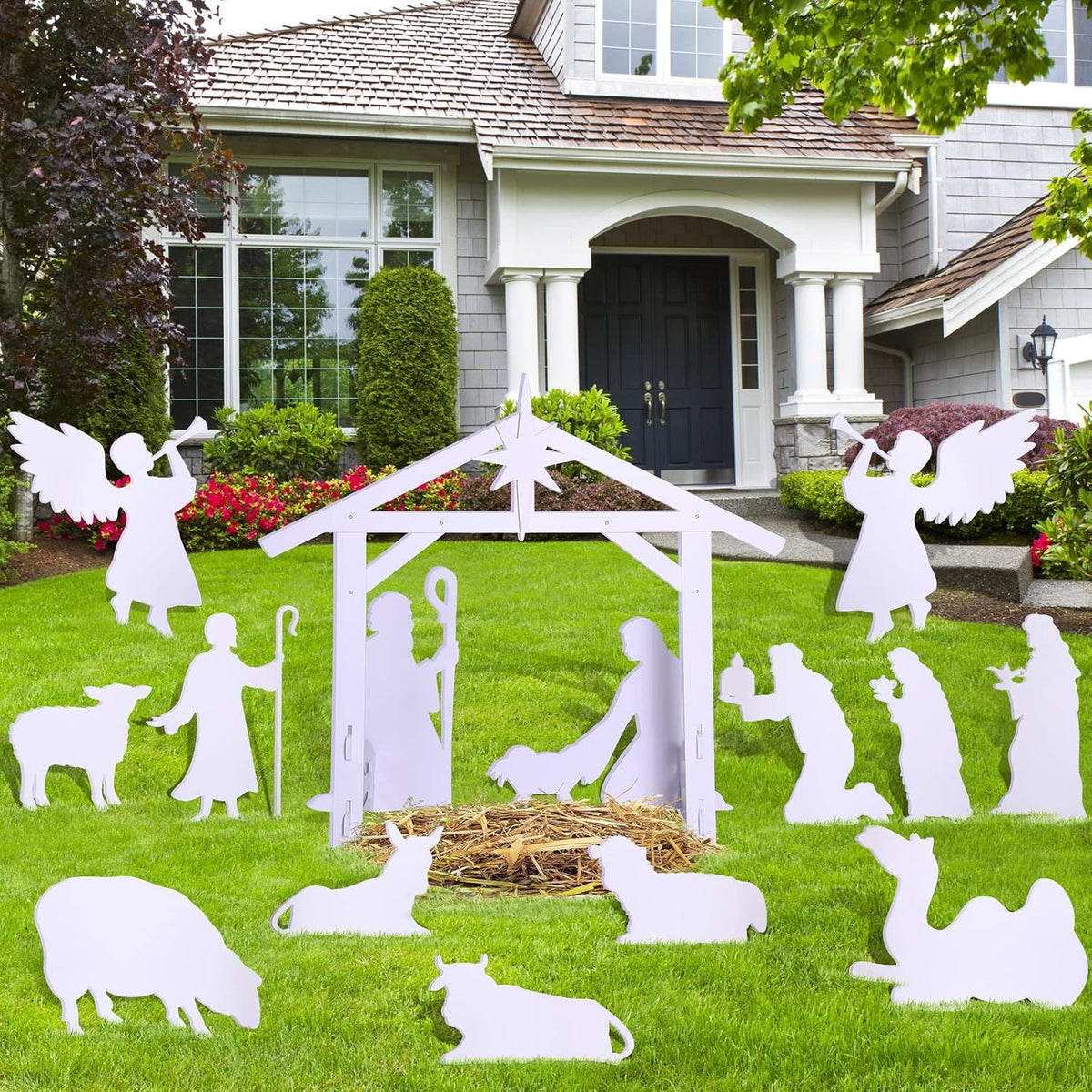 White silhouette nativity set with the stable, Holy Family, angels, kings, sheep and a camel on a green lawn