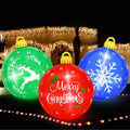 Three glowing inflatable Christmas ornament balls in green, red and blue on a lawn at night