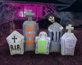 Row of gray tombstone inflatables marked RIP and Trick or Treat with a skull peeking over, lit purple