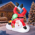 Inflatable Santa upside down in a snowbank with boots in the air and a green gift sack