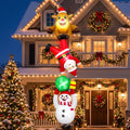 Tall chain of Christmas inflatables with a reindeer, Santa and a snowman hanging from a house roof