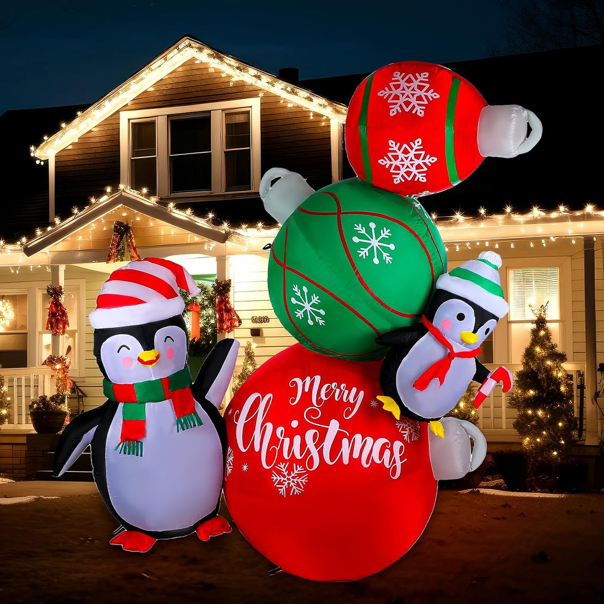 Two penguins in Santa hats beside stacked red and green ornament ball inflatables printed Merry Christmas
