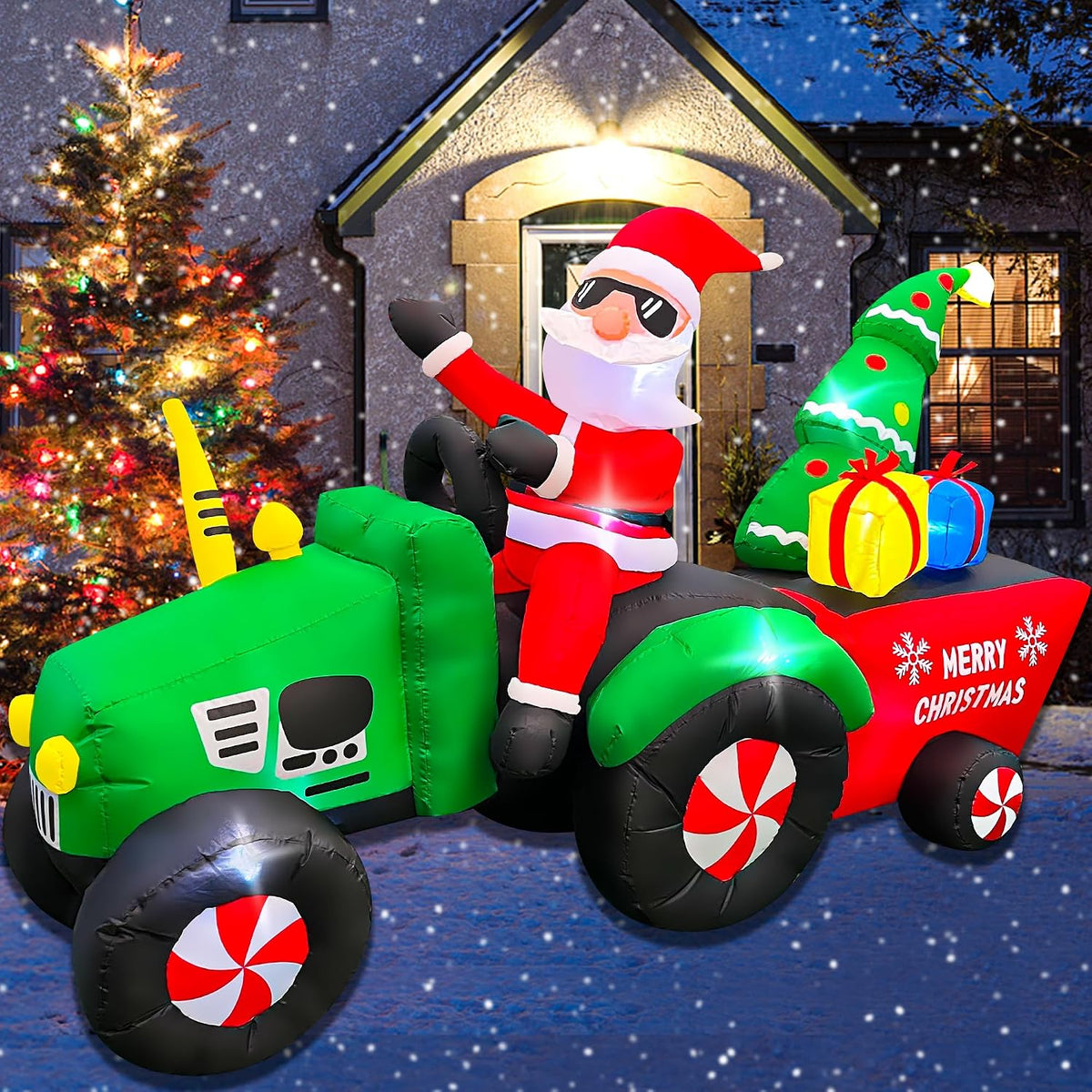 Santa in sunglasses driving a green tractor pulling a red Merry Christmas wagon with a tree and gifts