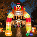 Striped Thanksgiving arch inflatable with a turkey and Happy Thanksgiving sign over a front walk at dusk