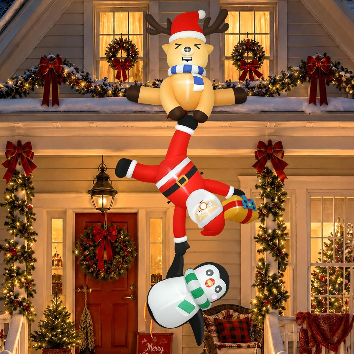 Hanging inflatable of a reindeer holding Santa who holds a penguin down the front of a decorated house
