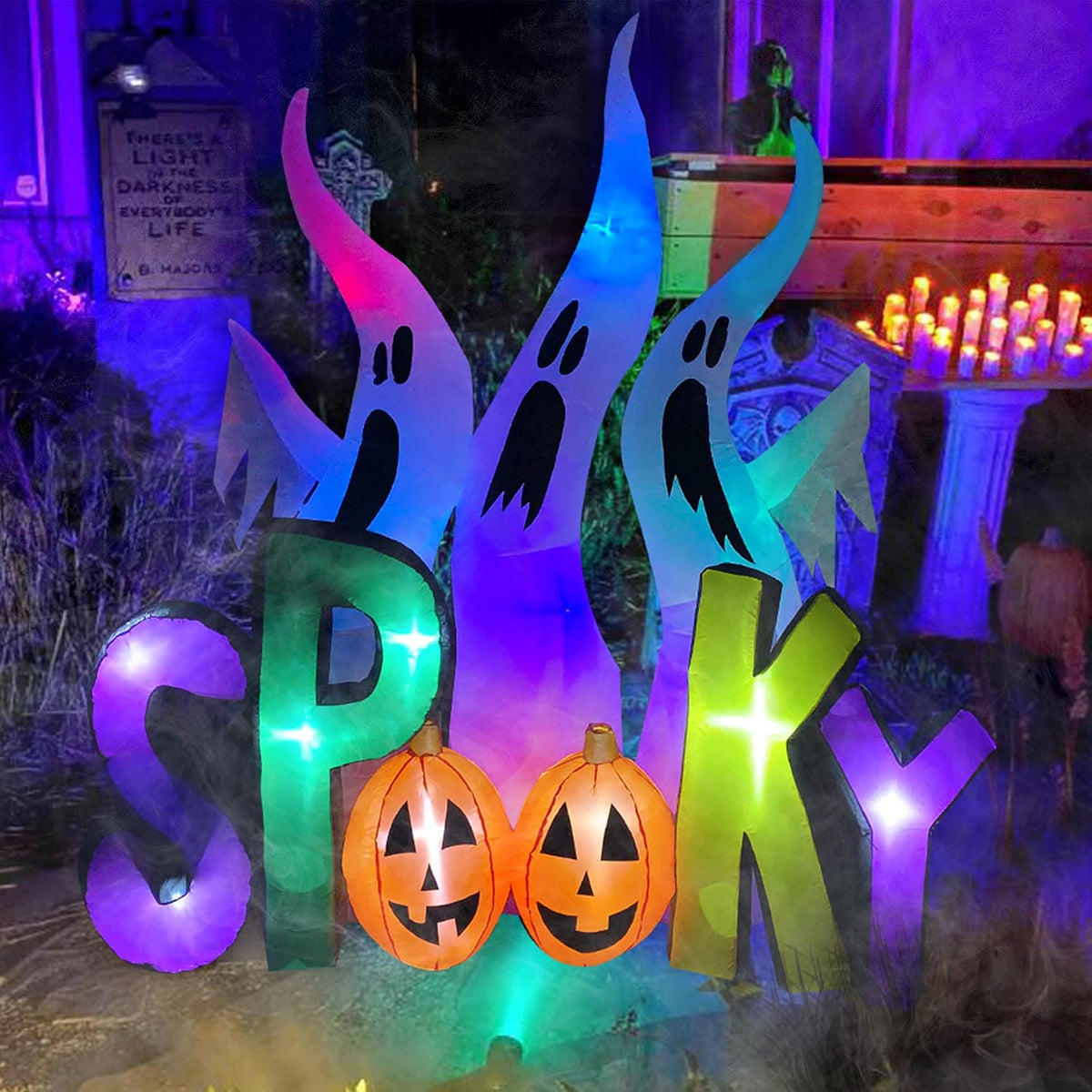 Three ghost inflatables behind giant letters spelling SPOOKY with pumpkin O's, lit purple and green